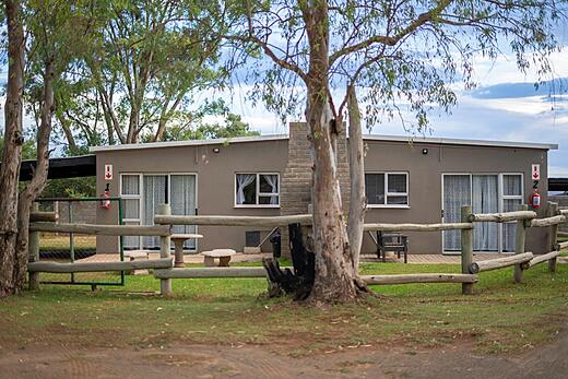 Guest building exterior with a timber fence and trees